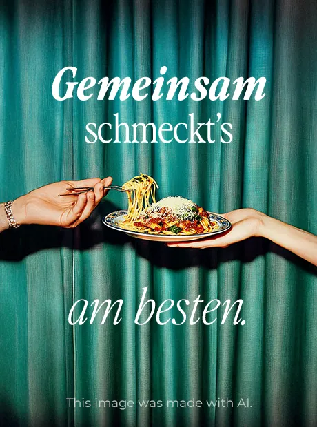 Eine Hand nimmt sich Nudeln von einem Teller Pasta vor einem dunkelgrünen Samtvorhang