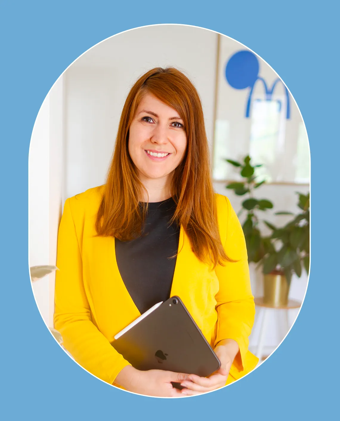 Kathrin Schönborn steht in ihrem Büro, lächelt in die Kamera und trägt einen gelben Blazer