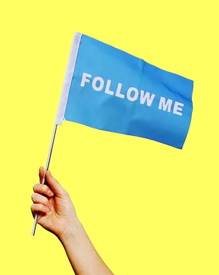 Eine Hand hält eine blaue Fremdenführerfahne vor einem gelben Hintergrund in die Luft